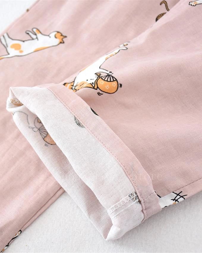 Détail d'un pantalon de kimono rose clair avec des motifs de chats blancs et oranges portant des paniers. Ourlet replié révélant un tissu à motifs plus discrets. Vêtement japonais confortable et tendance.