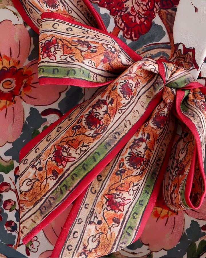 Détail d'un kimono fleuri avec une ceinture à motifs complexes, mise en valeur par des bordures rouges. Élégance et raffinement pour votre garde-robe. Découvrez nos kimonos uniques.