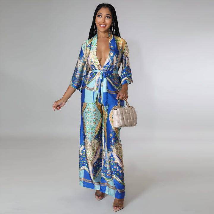 Femme portant un kimono bleu à motifs floraux, pantalon assorti, avec sac à main beige. Vêtements de détente élégants. Mode kimono.