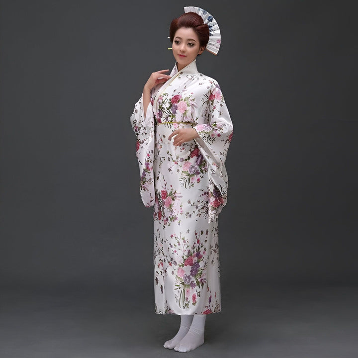 Femme en kimono blanc à motifs floraux colorés, tenant un éventail. Vente de kimonos japonais traditionnels et modernes.