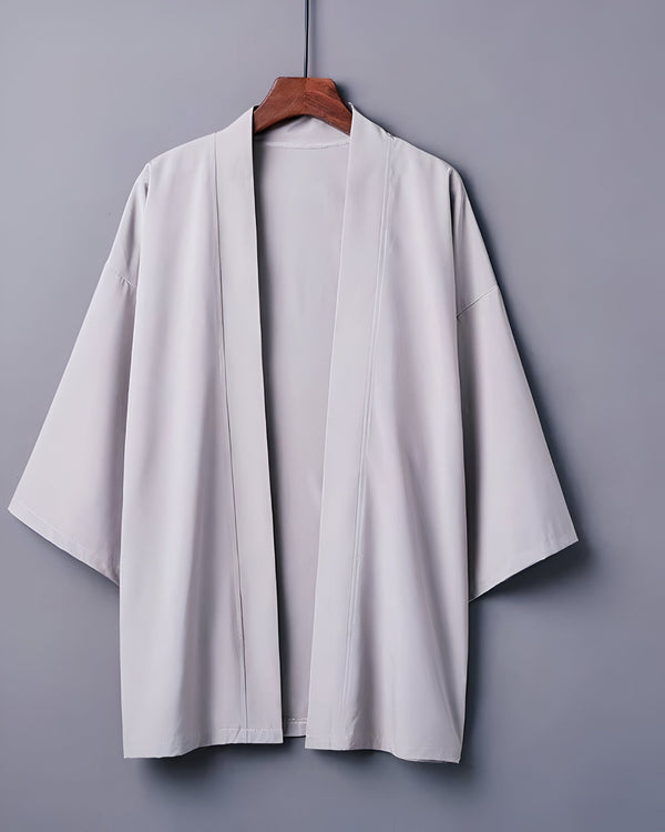 Kimono gris clair suspendu sur un cintre en bois. Vêtement traditionnel japonais, idéal comme veste légère ou peignoir. Découvrez notre collection de kimonos uniques !