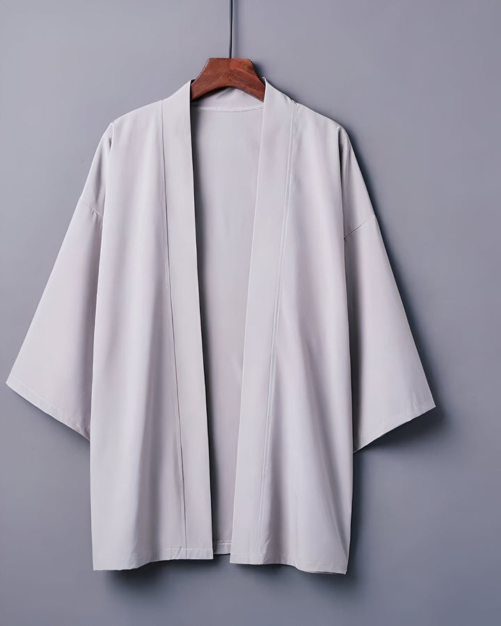 Kimono gris clair suspendu sur un cintre en bois. Vêtement traditionnel japonais, idéal comme veste légère ou peignoir. Découvrez notre collection de kimonos uniques !