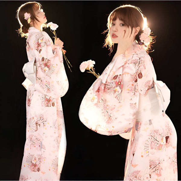 Deux jeunes femmes portant des kimonos traditionnels japonais à motifs floraux roses et blancs, fleurs dans les cheveux. Vente de kimonos authentiques.