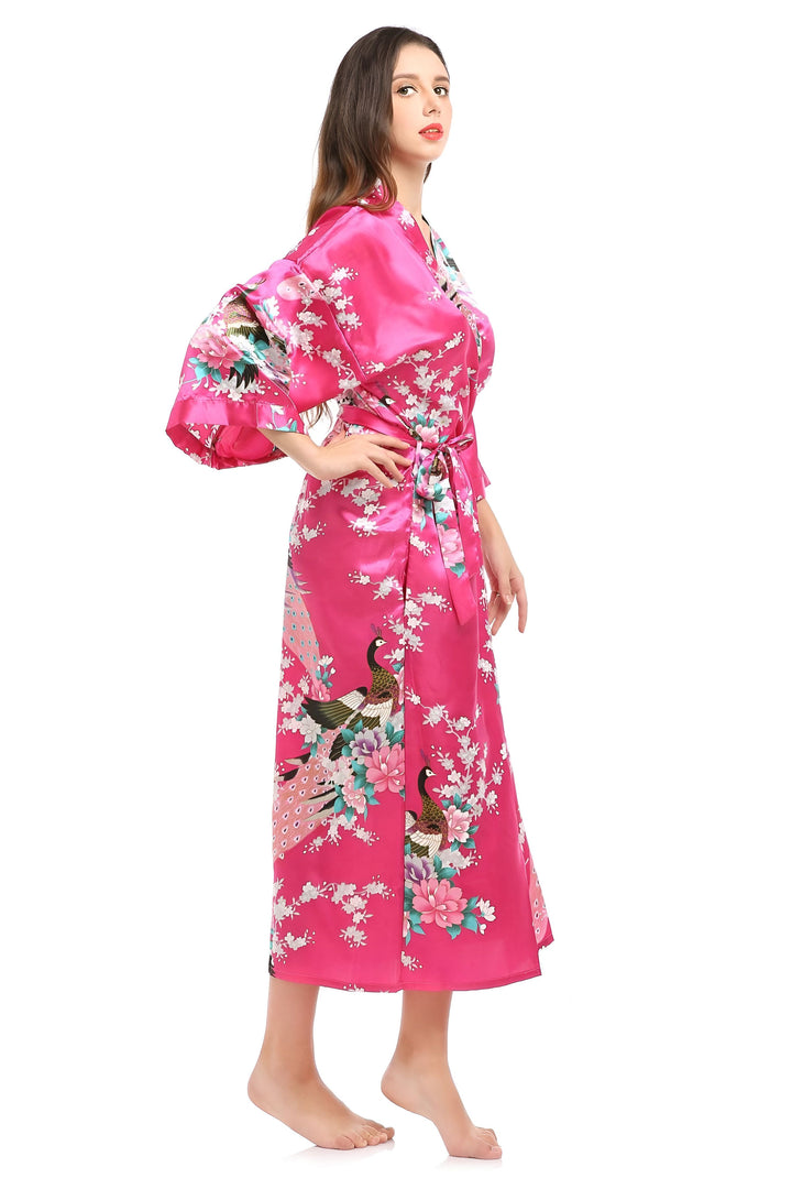 Femme portant un kimono rose imprimé paons et fleurs, vendu sur notre boutique en ligne. Vêtements de détente élégants et confortables.