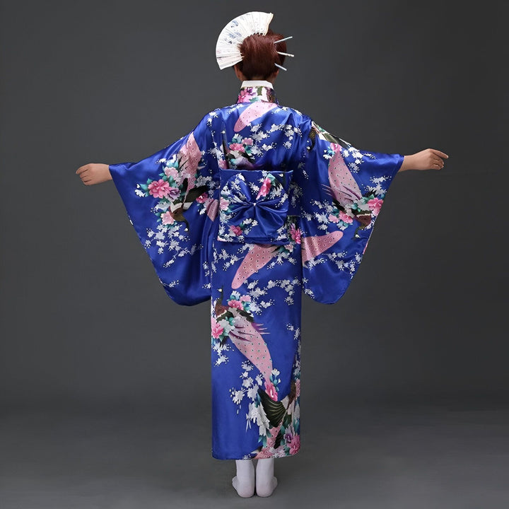 Femme vue de dos portant un kimono bleu avec motif floral et paon, coiffure avec éventail. Kimonos traditionnels japonais à vendre.