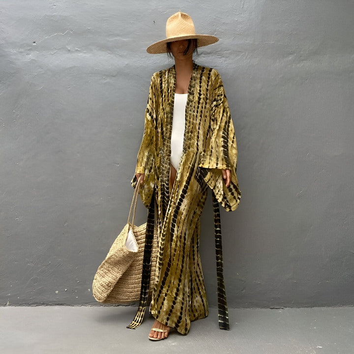 Femme portant un kimono long tie-dye marron et noir, un maillot de bain blanc, un chapeau de paille et un sac à main. Kimonos de style bohème chic en vente.