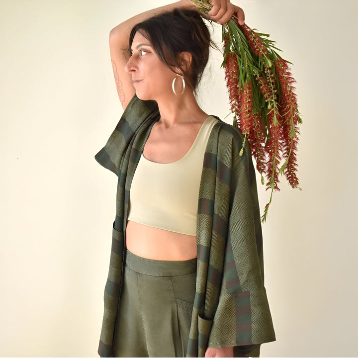 Femme portant un kimono à carreaux verts et rouges avec des fleurs. Découvrez notre collection de kimonos élégants pour toutes les occasions.