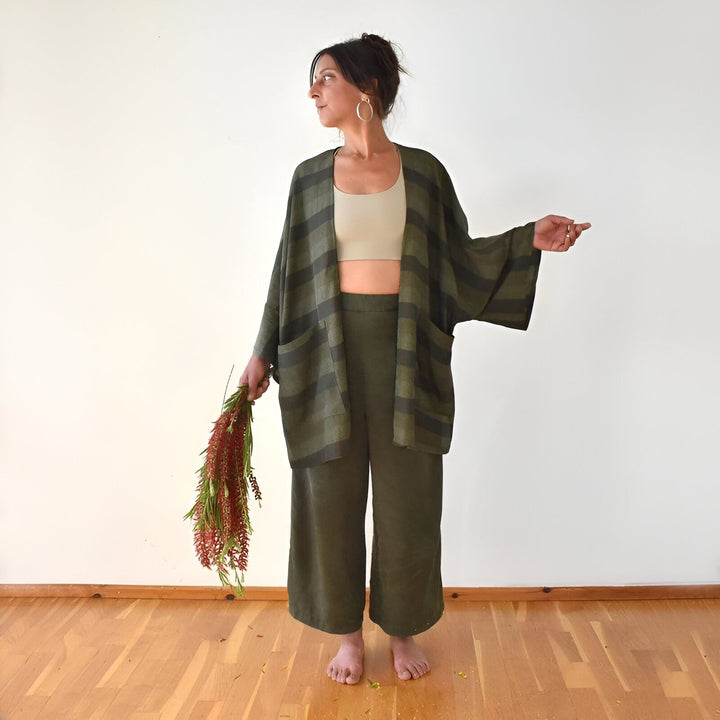 Femme portant un kimono vert rayé et un pantalon assorti. Kimono ample et décontracté avec poches. Vêtements confortables et élégants. Collection de kimonos en ligne.