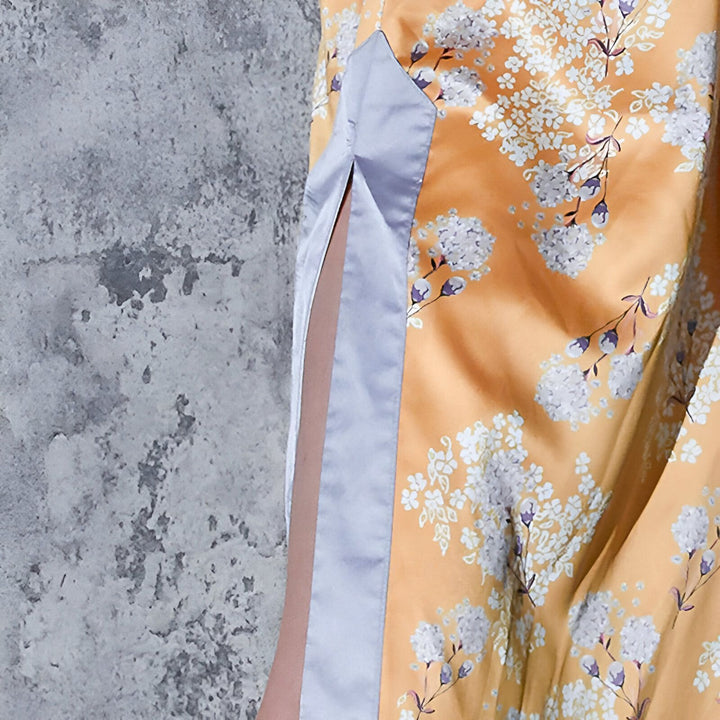 Détail d'un kimono floral jaune avec fente latérale et bordure lilas. Vêtements japonais traditionnels et modernes.
