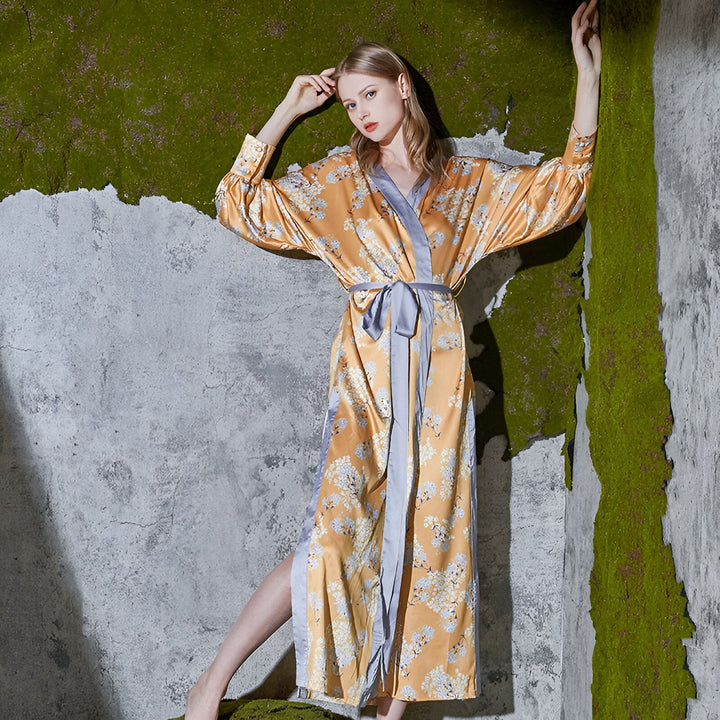 Femme portant un kimono long doré à motifs floraux. Kimono de style japonais avec ceinture. Vêtements traditionnels et modernes. Découvrez notre collection de kimonos uniques.