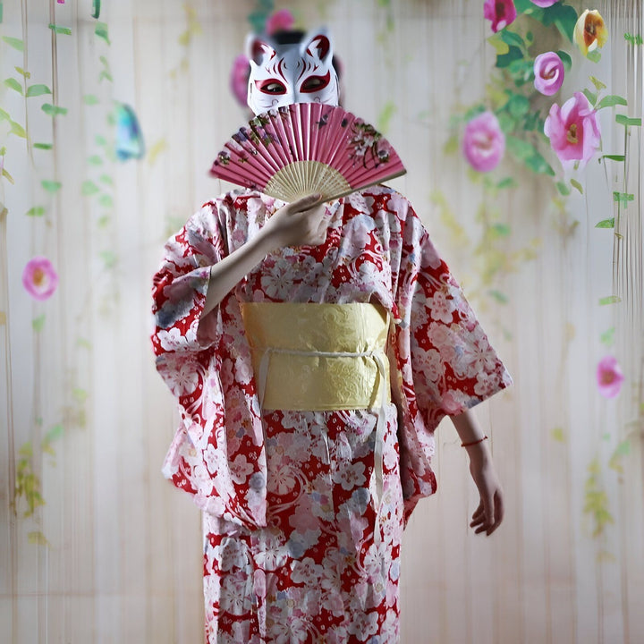 Kimono traditionnel rouge à motifs floraux, ceinture obi jaune, et masque de renard blanc. Éventail rose. Vente de kimonos authentiques.
