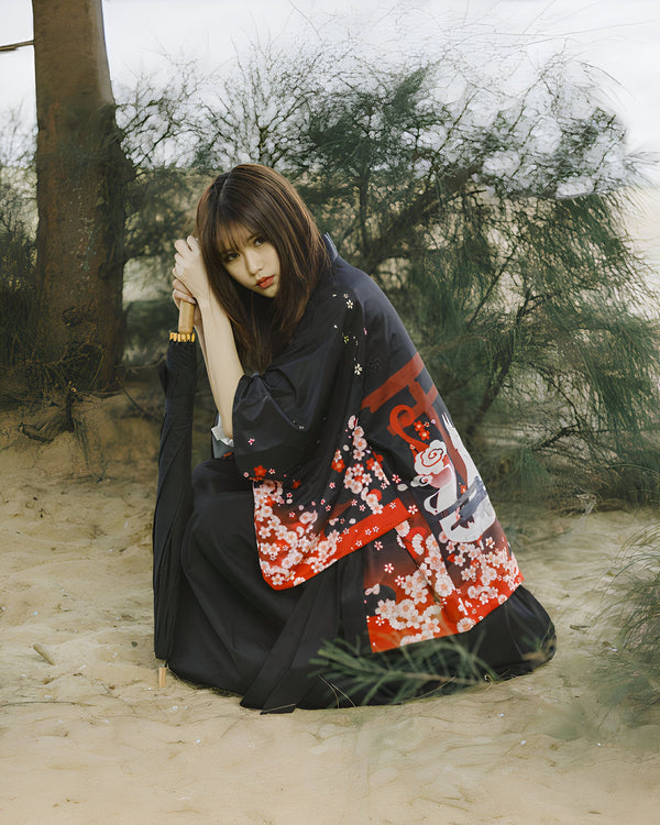 Femme en kimono noir fleuri, assise dans le sable, tenant un parasol. Kimonos traditionnels et modernes à vendre. Mode japonaise authentique.