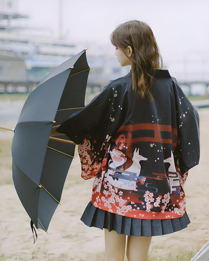 Femme vue de dos portant un kimono noir à motifs floraux et renards, tenant un parapluie. Vente de kimonos en ligne. Mode japonaise, style unique et élégant. Découvrez notre collection de kimonos.