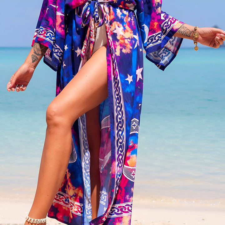 Femme portant un kimono coloré sur la plage. Kimono avec motifs d'étoiles, bleu et rose. Vêtements de plage tendance. Boutique en ligne de kimonos.