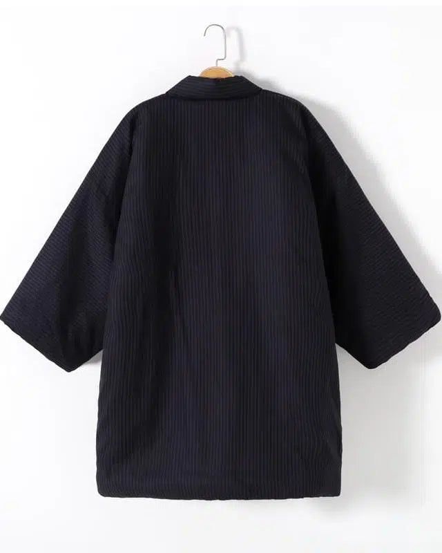 Kimono noir en velours côtelé suspendu. Vêtement japonais traditionnel avec manches amples. Collection de kimonos.