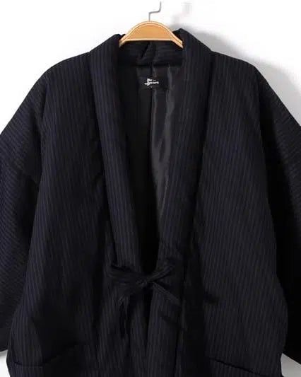 Kimono pour homme à rayures suspendu à un cintre. Vêtement traditionnel japonais, idéal pour un style unique et élégant. Découvrez notre collection de kimonos de qualité.