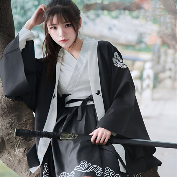 Femme portant un kimono traditionnel noir et blanc avec un katana. Kimonos authentiques et élégants disponibles dans notre boutique. Découvrez notre collection unique!