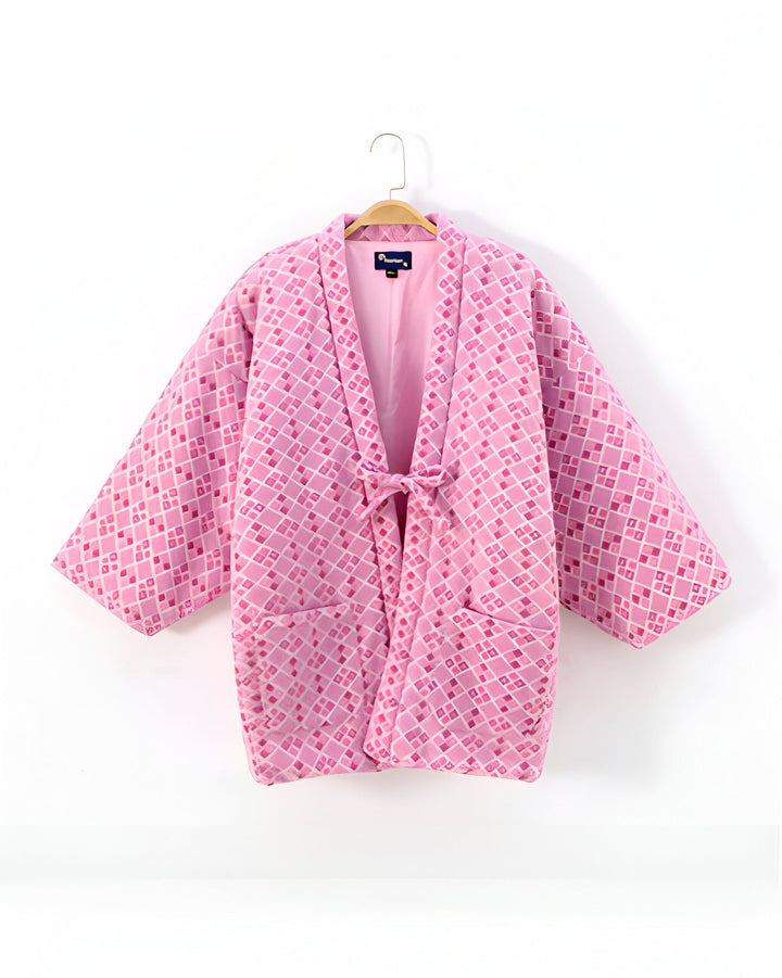Kimono rose à motifs géométriques suspendu sur un cintre. Vêtement de style japonais, idéal pour un look unique et tendance. Découvrez notre collection de kimonos.