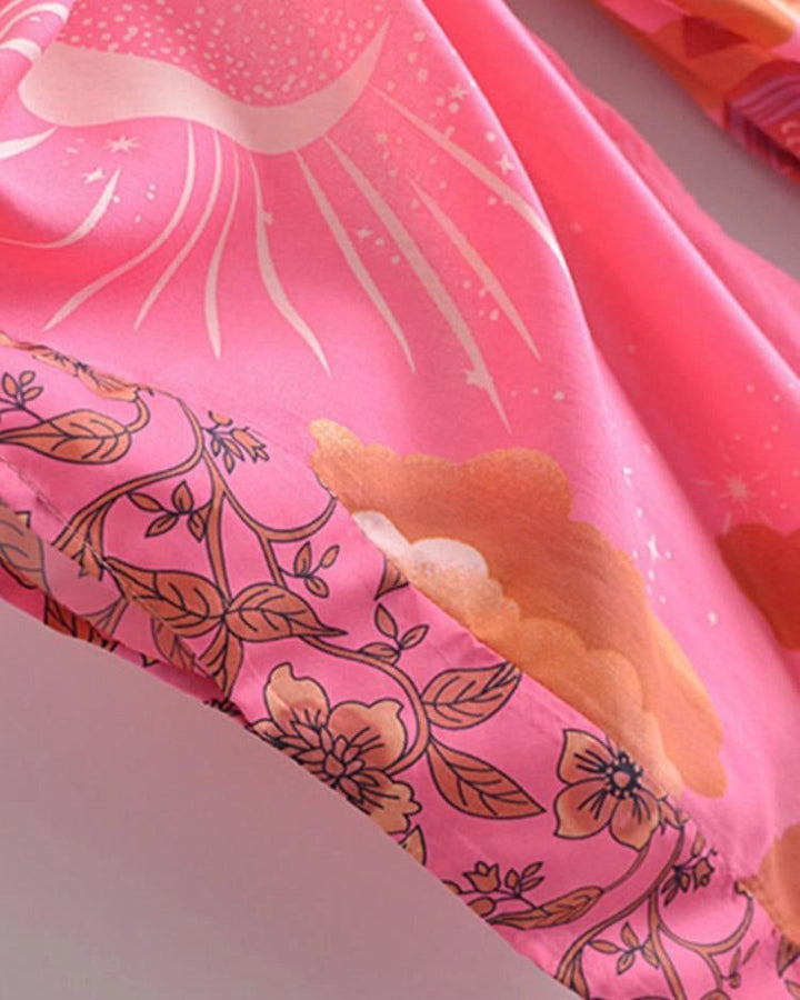 Détail d'un kimono rose avec motifs de soleil, nuages et fleurs. Textile léger et coloré, parfait pour un look bohème chic. Découvrez notre collection de kimonos uniques.