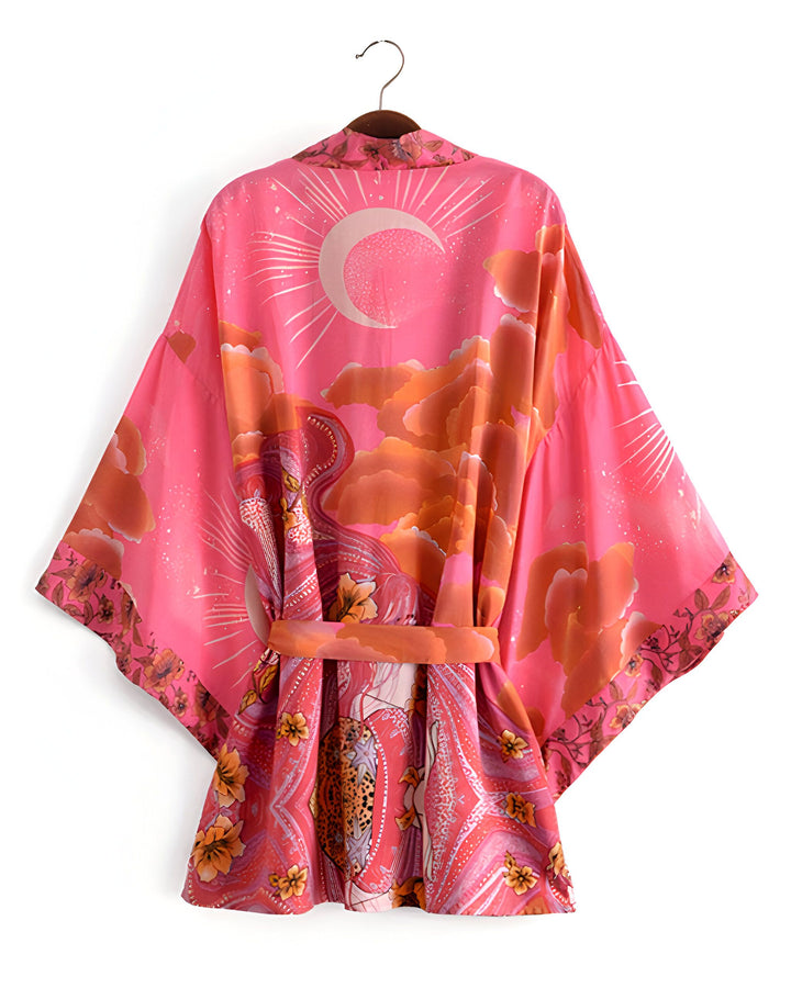 Kimono rose bohème avec imprimé lune, nuages et motifs floraux. Vêtement ample et léger, idéal pour un look estival unique. Découvrez notre collection de kimonos.