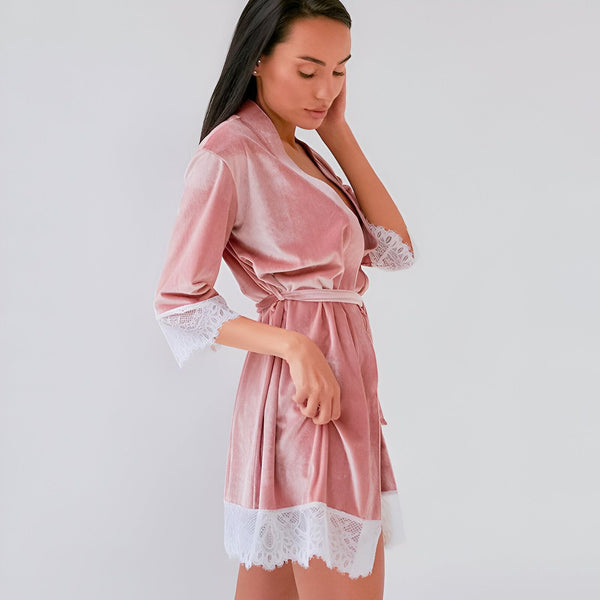 Femme portant un kimono rose en velours avec détails en dentelle blanche. Élégance et confort pour se détendre avec style. Kimono parfait pour votre routine beauté ou comme vêtement d'intérieur luxueux.