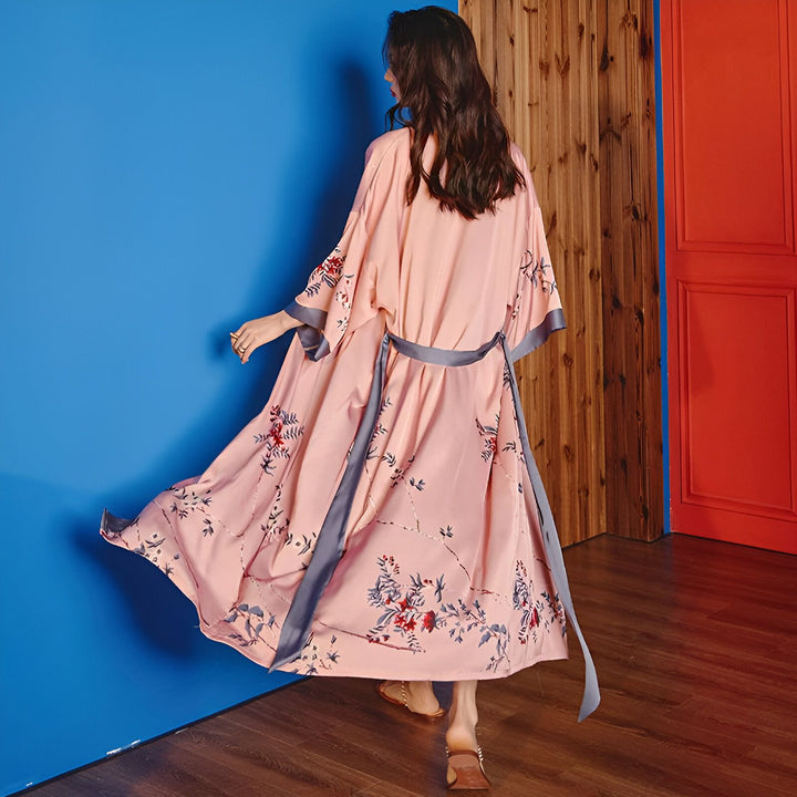 Femme portant un kimono rose à motifs floraux, vue de dos. Kimono de qualité, idéal pour la maison ou comme vêtement d'extérieur. Découvrez notre collection de kimonos uniques et élégants.
