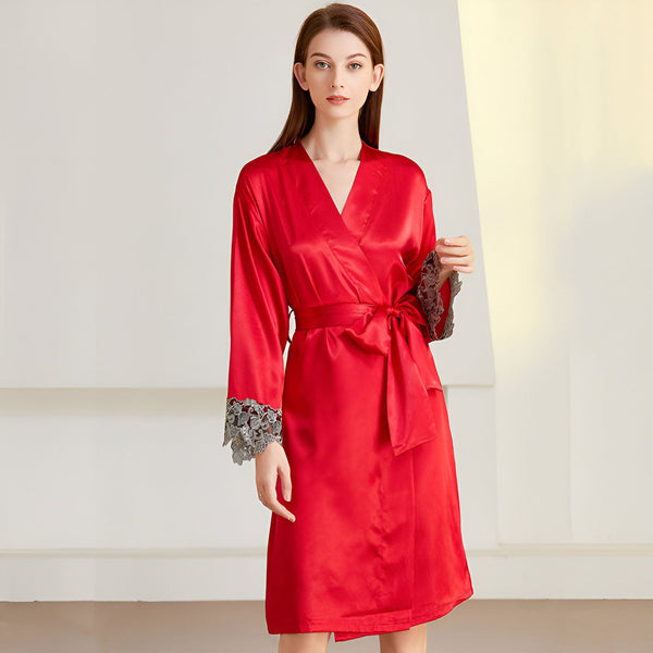 Femme portant un kimono rouge en soie avec des finitions en dentelle grise aux manches. Ceinture assortie nouée à la taille. Fond clair.