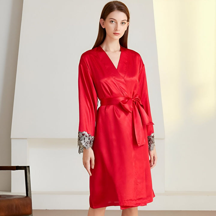 Femme portant un peignoir rouge en soie avec des détails en dentelle grise sur les manches. Le peignoir est ceinturé et a un col en V.