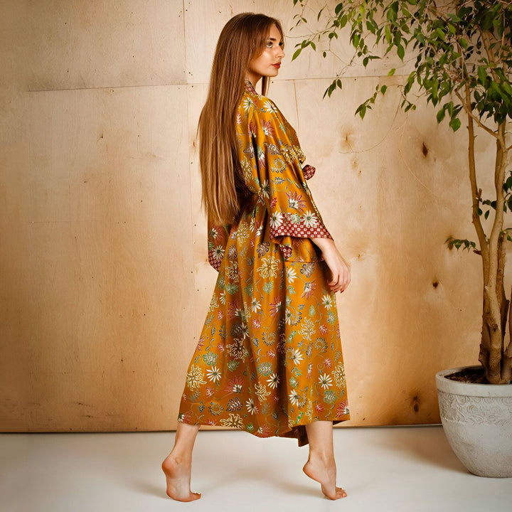 Femme portant un kimono long fleuri, tons chauds. Idéal comme vêtement d'intérieur ou d'extérieur léger. Collection de kimonos élégants et confortables en vente.