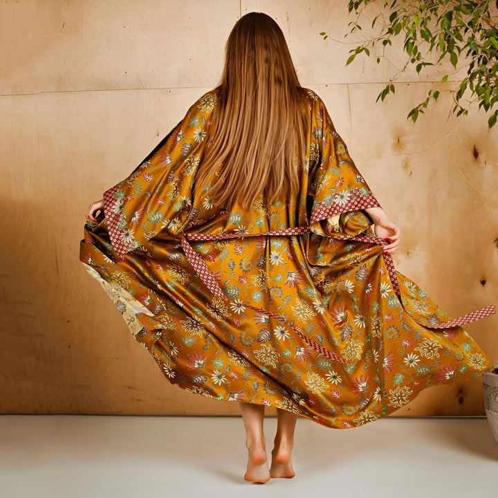 Femme portant un kimono doré à motifs floraux. Vente de kimonos uniques et élégants en ligne. Découvrez notre collection de kimonos de haute qualité. Kimono avec ceinture. Mode japonaise.