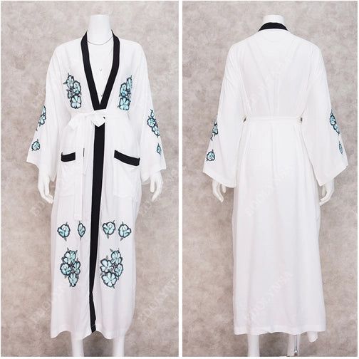 Vue avant et arrière d'un peignoir long blanc avec bordure noire et broderies florales turquoise.
