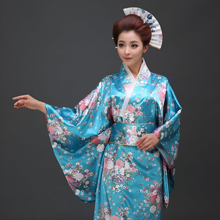 Femme portant un kimono bleu à fleurs, coiffée d'un chignon et d'un éventail. Costume traditionnel japonais.