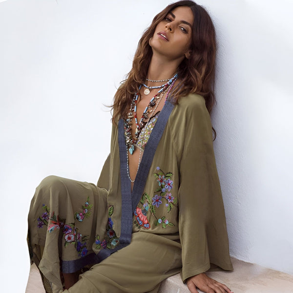Femme portant un kimono vert olive brodé de fleurs. Elle porte plusieurs colliers. Kimono à manches longues, style bohème chic. Vêtements pour femmes, collection kimono.