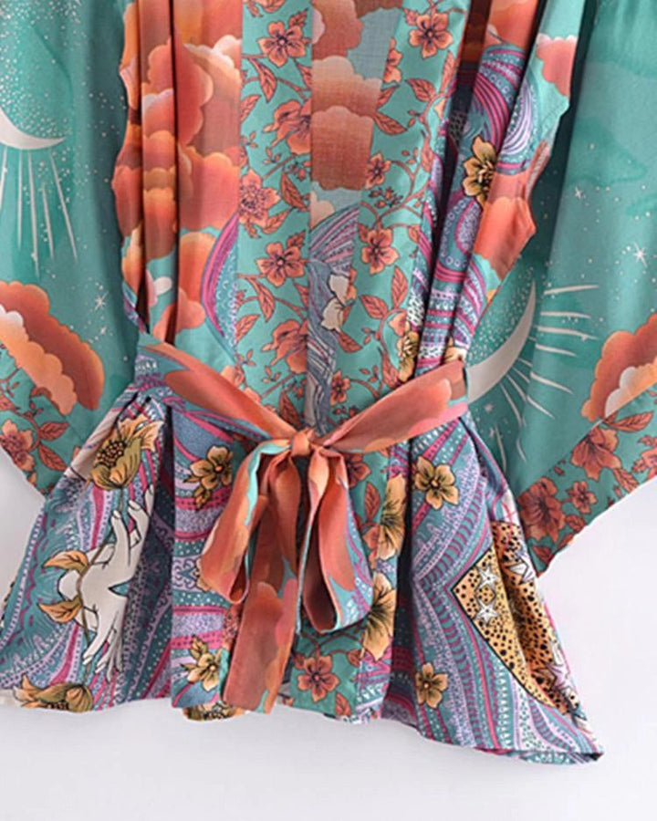 Kimono pour femme avec motifs floraux, lunes et nuages, noué à la taille. Vêtement léger et coloré, idéal pour un look bohème chic. Découvrez notre collection de kimonos originaux !