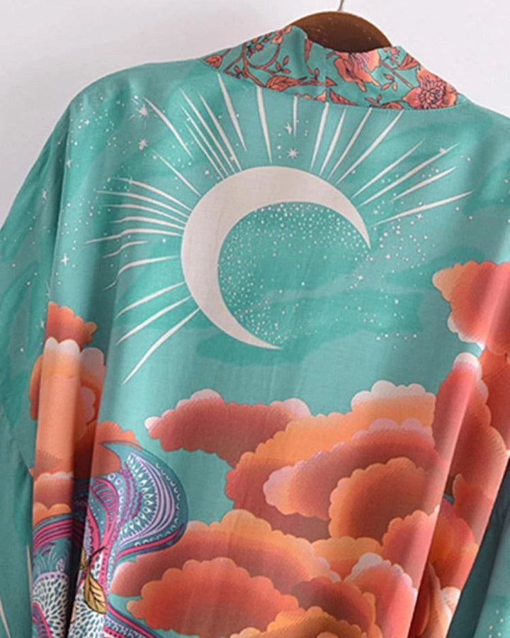 Kimono turquoise avec imprimé lune, nuages orange et détails floraux. Vêtement de style japonais, idéal pour un look bohème chic. Découvrez notre collection de kimonos uniques.