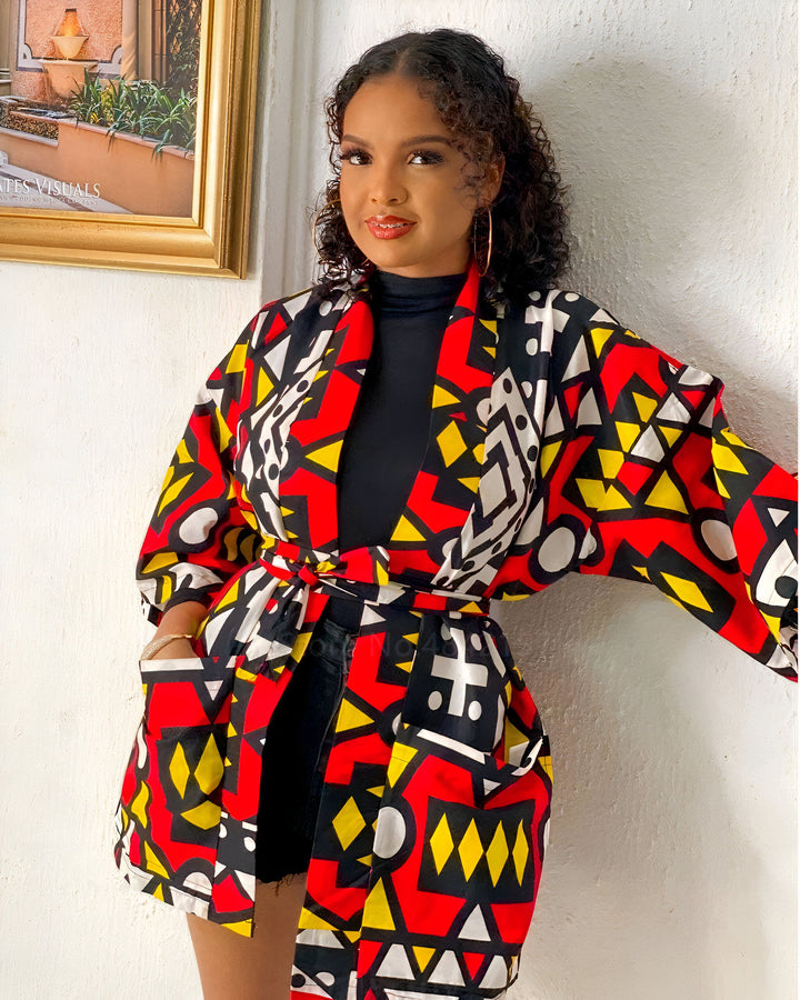 Femme portant un kimono coloré avec motifs géométriques rouges, jaunes et noirs. Vêtement tendance et stylé, idéal pour rehausser votre garde-robe. Découvrez notre collection de kimonos uniques!
