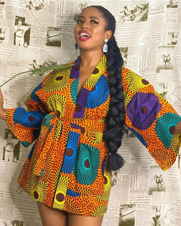 Jeune femme souriante portant un kimono coloré à motifs africains. Vêtements kimono élégants et uniques à acheter en ligne.