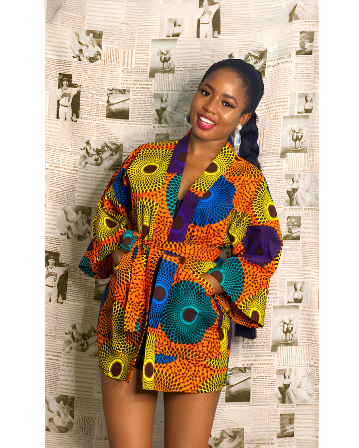 Femme souriante portant un kimono coloré à motifs africains. Notre collection de kimonos tendance pour toutes les occasions.