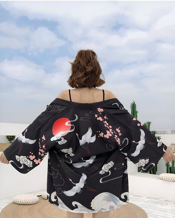 Kimono noir avec motifs de grues blanches, fleurs de cerisier et soleil rouge. Vêtement traditionnel japonais revisité, parfait pour un look unique et tendance. Notre collection de kimonos offre des designs variés.