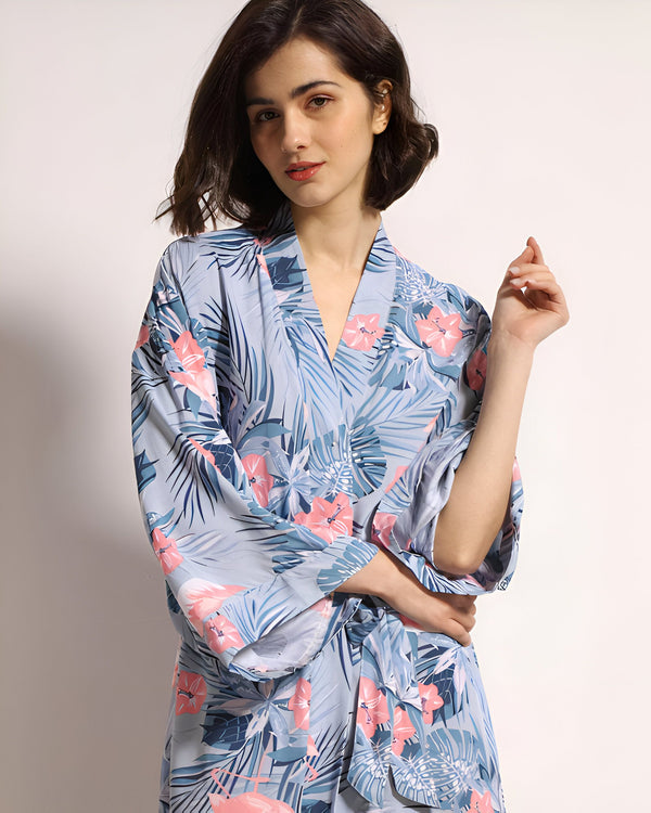 Femme portant un kimono bleu à motifs floraux roses et feuilles tropicales bleues. Vente de kimonos pour femmes.