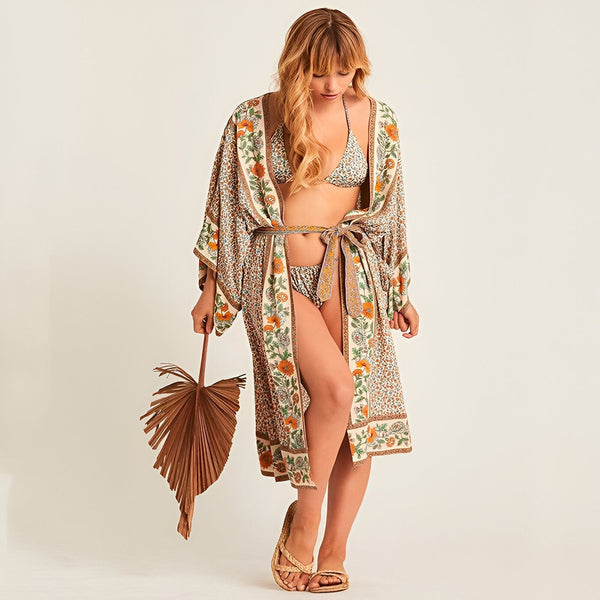 Femme portant un kimono floral beige et orange, assorti à un bikini. Look estival bohème et décontracté, idéal pour la plage ou la détente. Vente de kimonos en ligne.