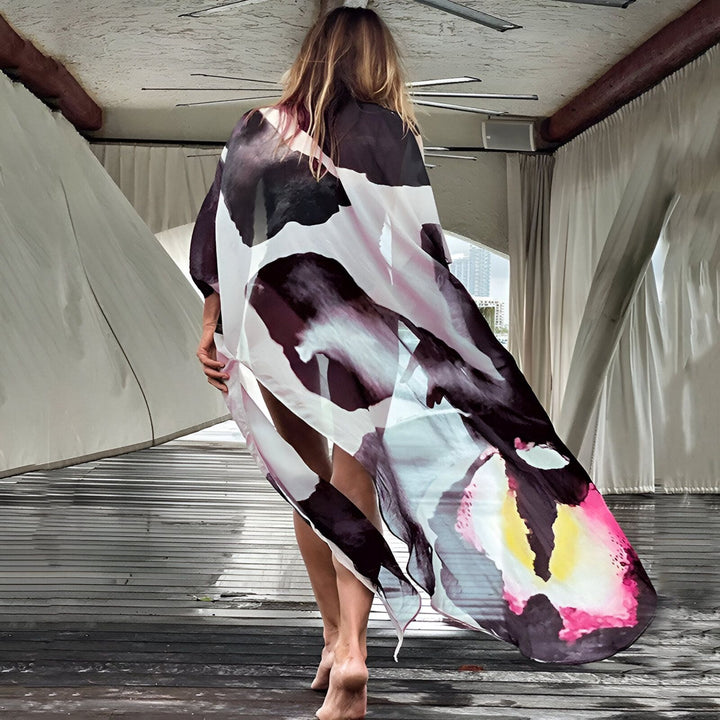 Femme portant un kimono coloré, dos tourné. Kimono à motifs abstraits noirs, blancs, roses et jaunes. Collection de kimonos tendance.