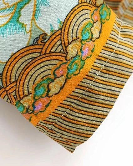 Détail d'un kimono avec motif floral et vagues orange. Tissu rayé orange et noir sur le bord de la manche. Kimonos disponibles à l'achat.