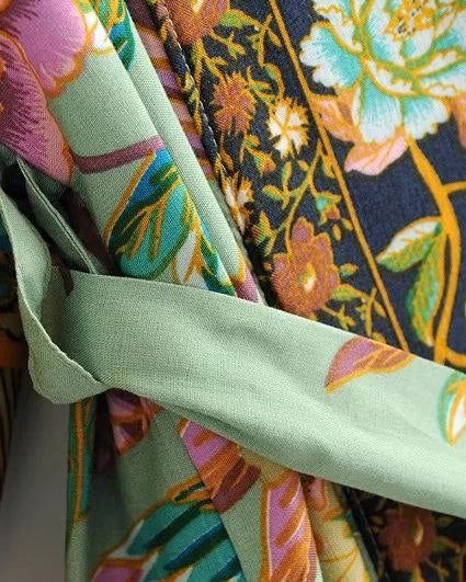 Détail d'un kimono fleuri en tissu soyeux. Motifs floraux complexes et ceinture verte unie. Vêtements japonais traditionnels avec une touche moderne. Collection kimono en ligne.