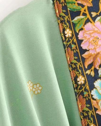 Détail d'un kimono avec motif floral et bordure ornementale. Tissu vert clair avec petites fleurs. Vêtements de style kimono à motifs floraux.