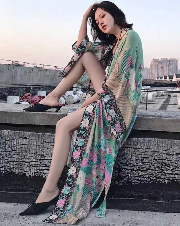 Femme élégante portant un kimono fleuri turquoise et rose. Vêtements d'extérieur style kimono à motifs floraux, idéal pour un look décontracté et tendance. Notre collection de kimonos pour toutes les occasions.