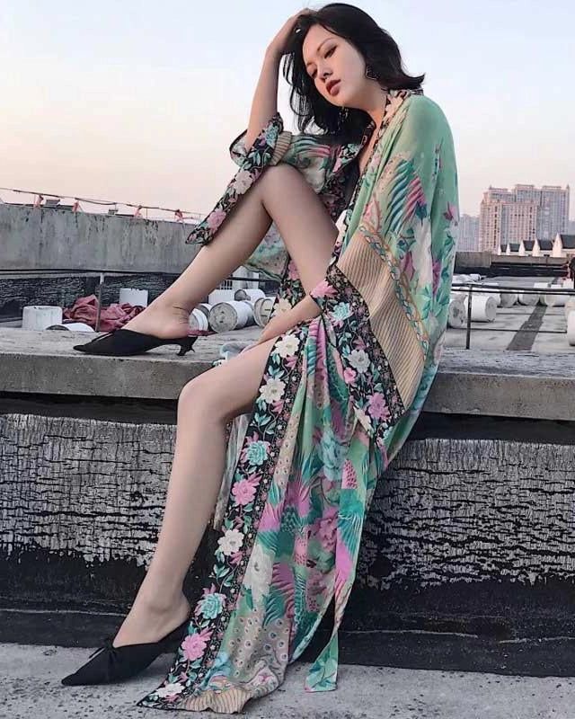 Femme élégante portant un kimono fleuri turquoise et rose. Vêtements d'extérieur style kimono à motifs floraux, idéal pour un look décontracté et tendance. Notre collection de kimonos pour toutes les occasions.