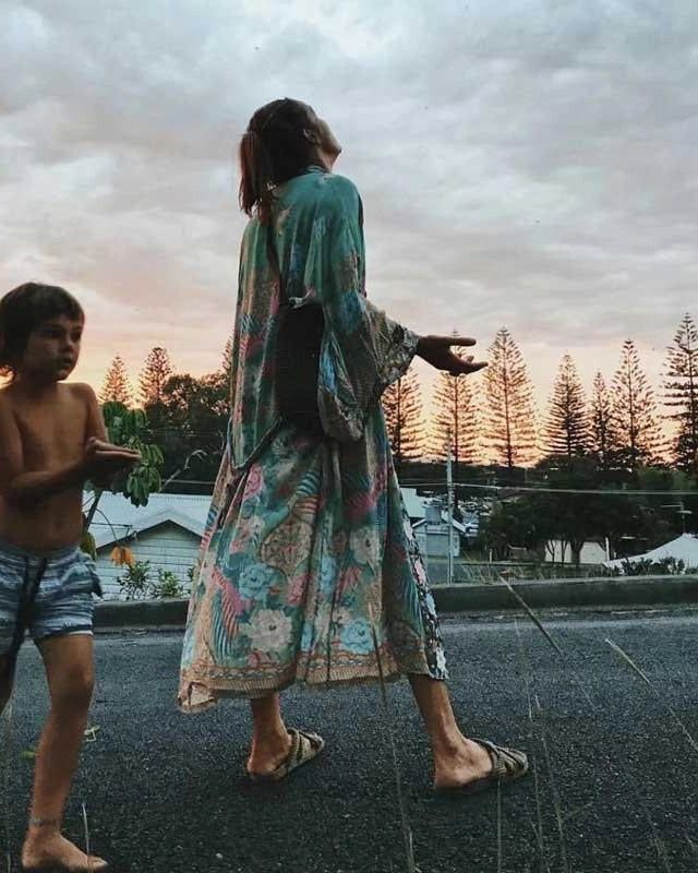 Femme portant un kimono fleuri avec un enfant au coucher du soleil. Collection de kimonos pour femme. Mode bohème, vêtements d'été.
