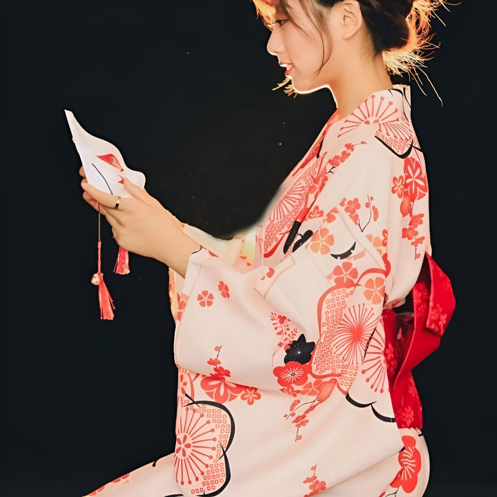 Femme en kimono traditionnel japonais à motifs floraux, tenant un masque de renard blanc. Vêtements japonais authentiques, mode kimono, boutique de kimonos.