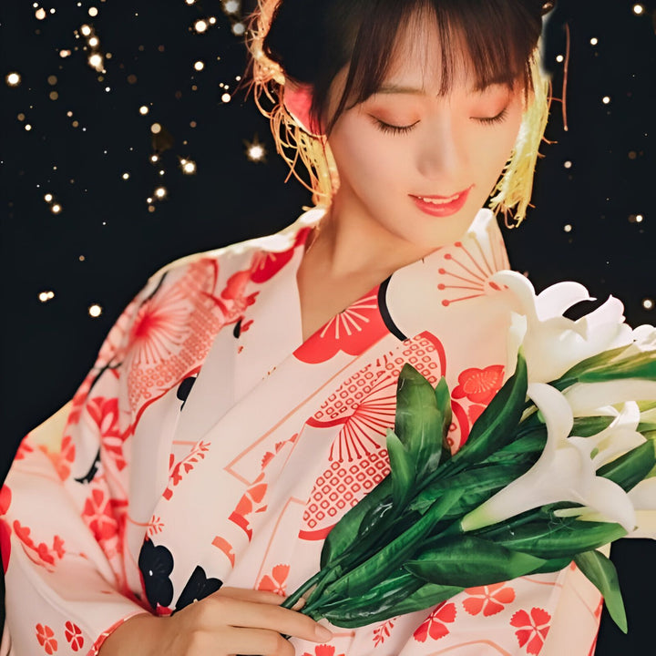 Femme en kimono traditionnel japonais rose et rouge, tenant un bouquet de lys blancs. Élégance et culture japonaise. Découvrez notre collection de kimonos uniques.
